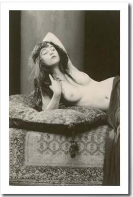 black and white vintage nude photo of a woman with pillow and rug